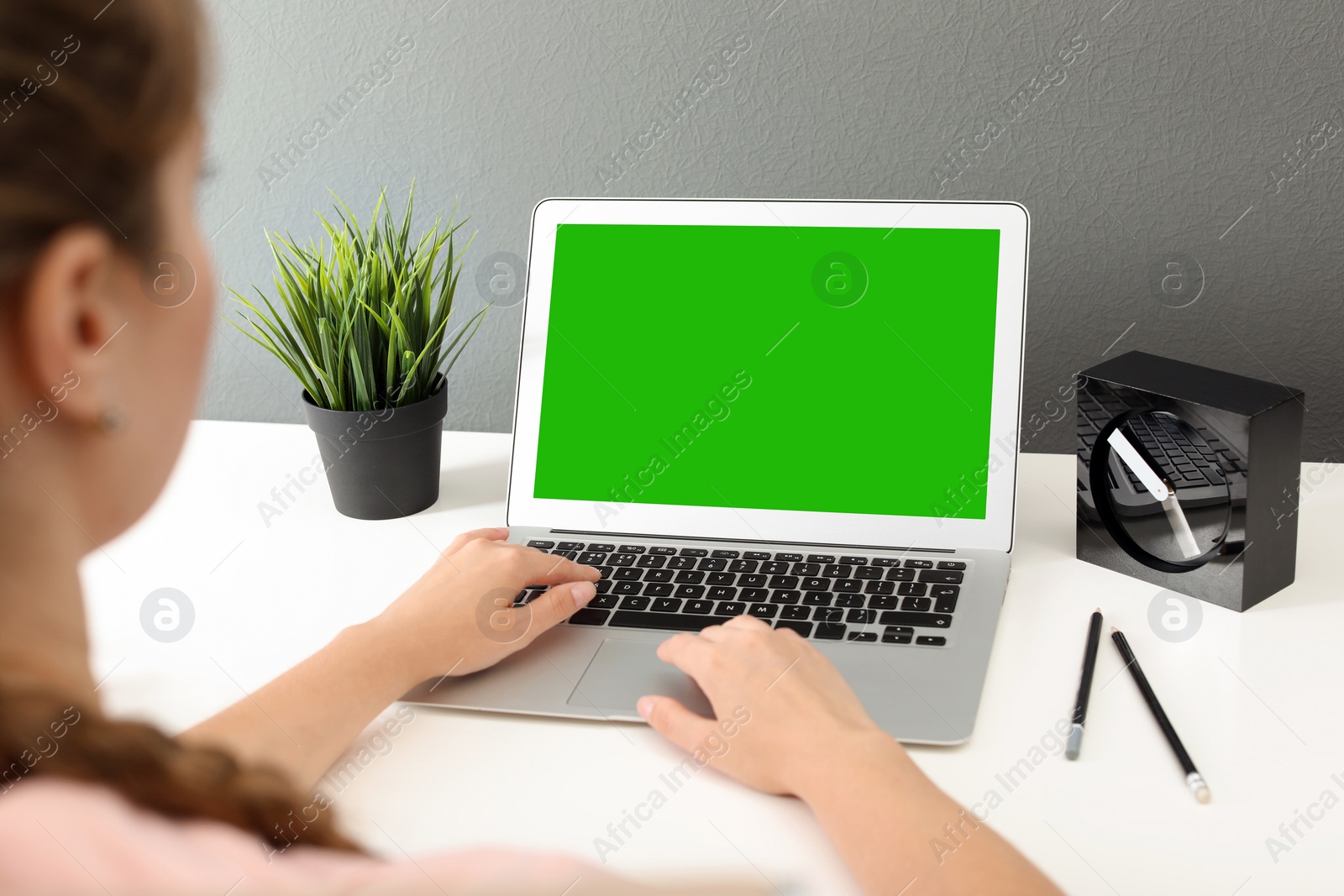 Image of Woman using laptop at white desk, closeup. Device display with chroma key