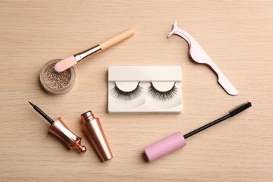 Photo of Flat lay composition with magnetic eyelashes and accessories on wooden table