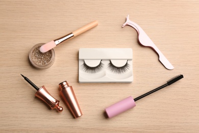 Flat lay composition with magnetic eyelashes and accessories on wooden table