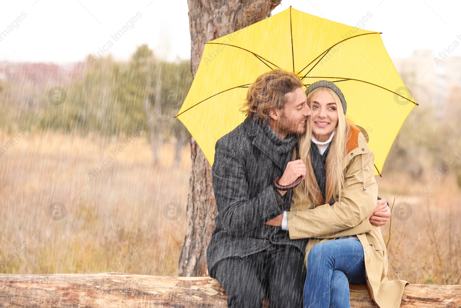 Photo of Young romantic couple with umbrella in park on autumn day