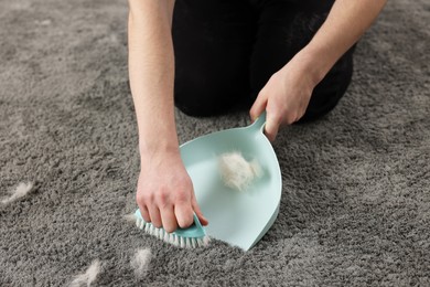 Man with brush and pan removing pet hair from carpet, closeup