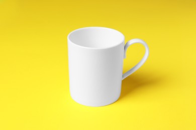Photo of One white ceramic mug on yellow background