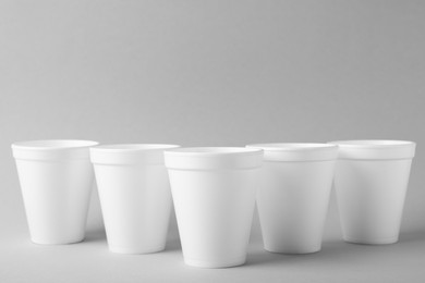 Many takeaway styrofoam cups on light grey background