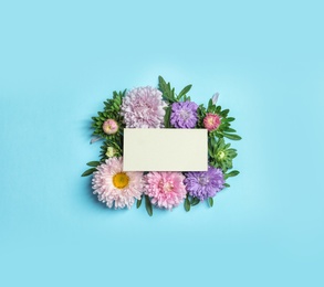 Photo of Beautiful aster flowers with sheet of paper on color background, top view. Space for text