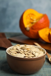 Photo of Bowl of raw pumpkin seeds on blue wooden table