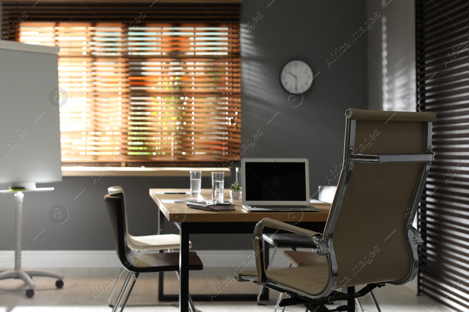 Photo of Stylish office interior with wooden table and flipchart