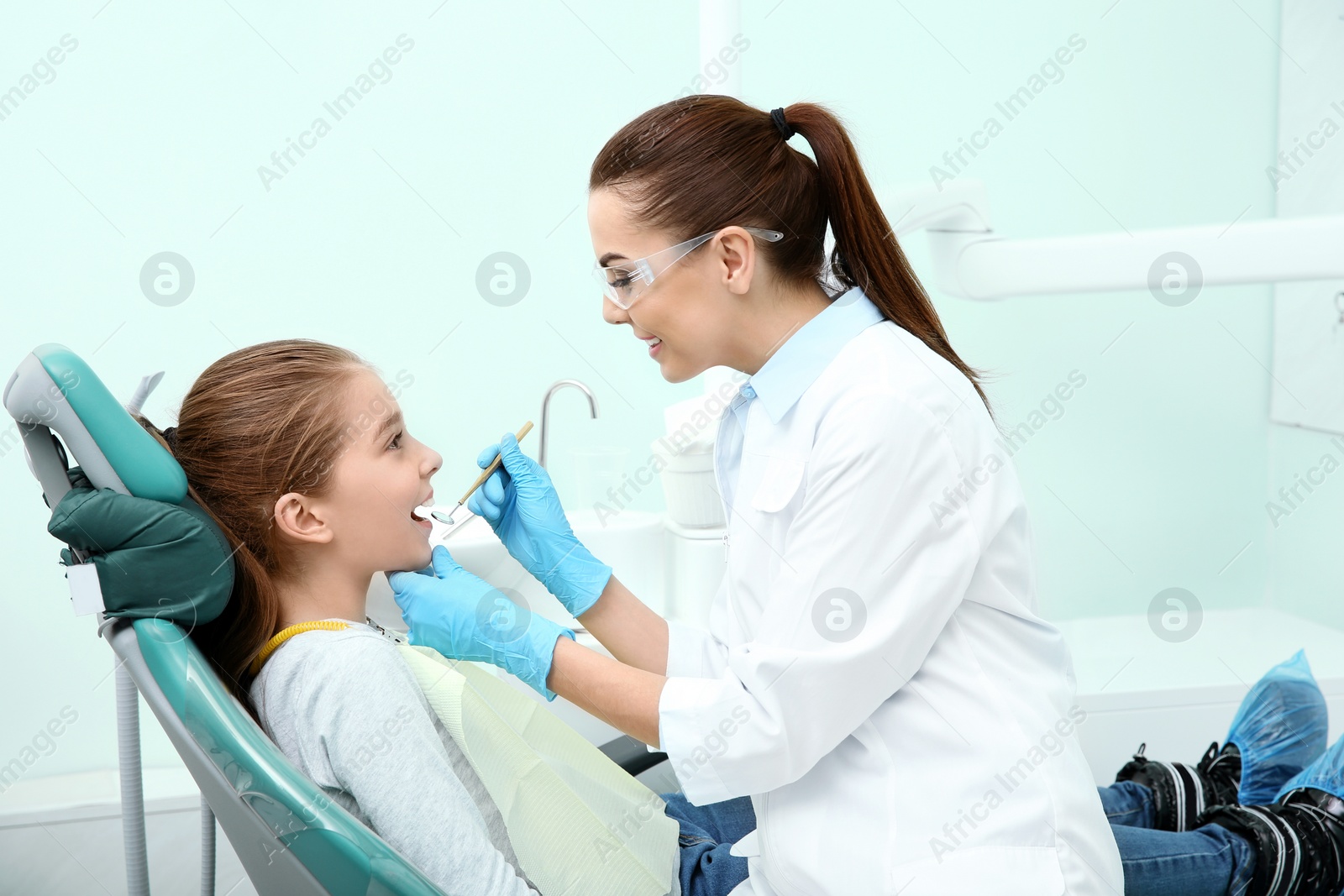 Photo of Professional dentist working with little patient in modern clinic