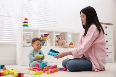 Photo of Cute baby boy playing with mother and building blocks on floor at home