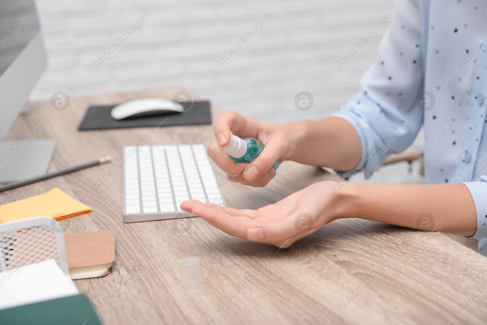 Photo of Office employee applying hand sanitizer at workplace, closeup