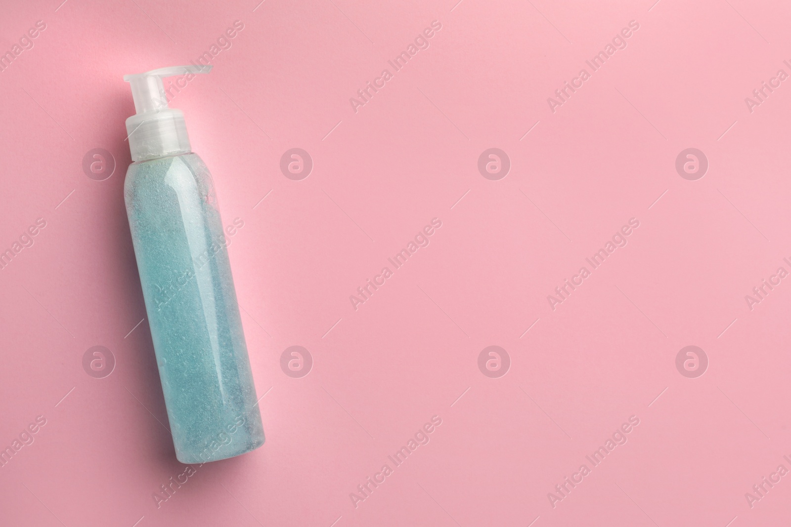 Photo of Bottle of blue cosmetic gel on pink background, top view. Space for text