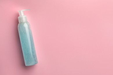 Photo of Bottle of blue cosmetic gel on pink background, top view. Space for text