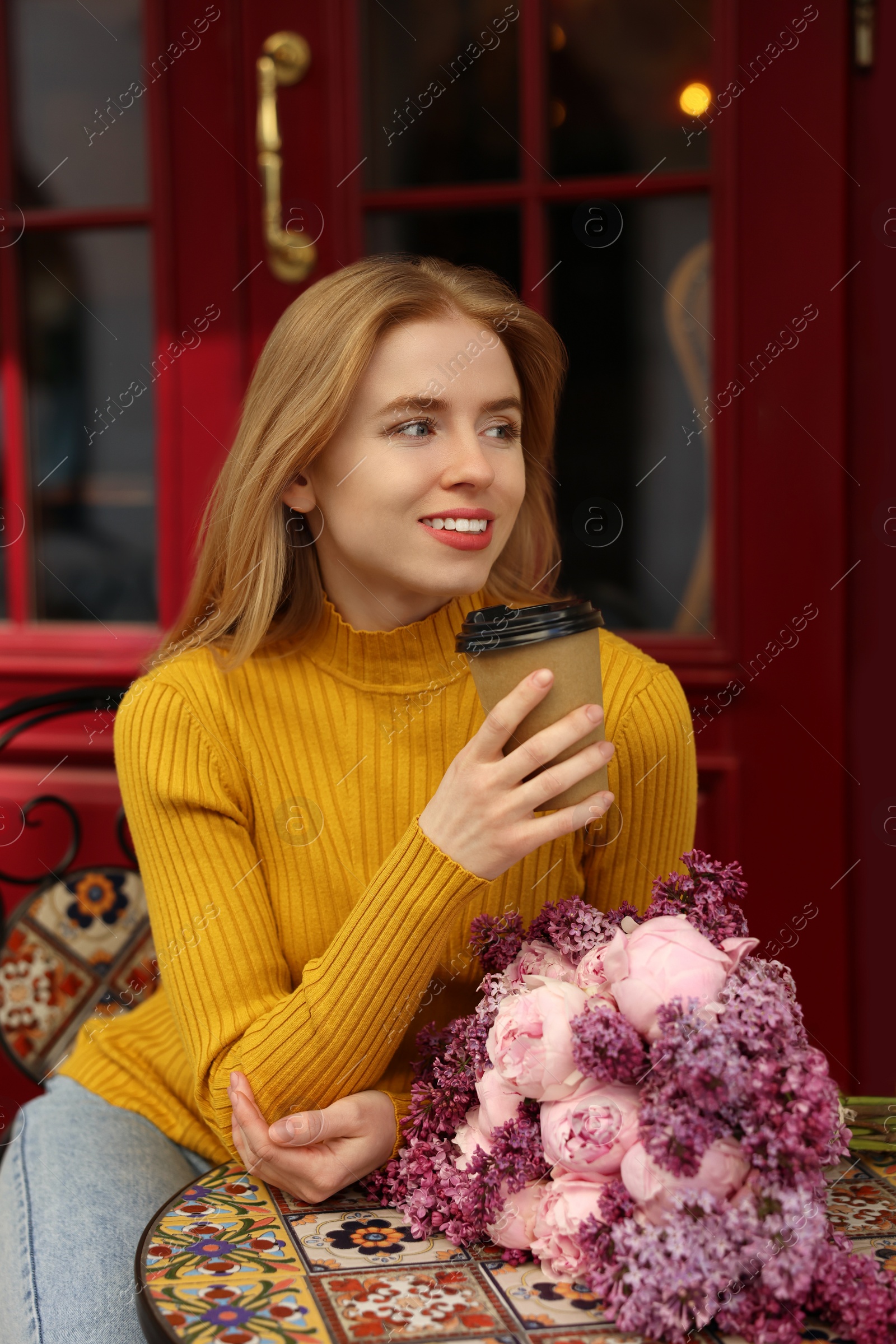 Photo of Beautiful woman with bouquet of spring flowers and coffee in outdoor cafe