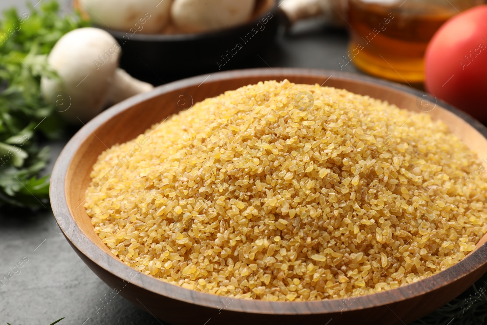 Photo of Raw bulgur in bowl on table, closeup