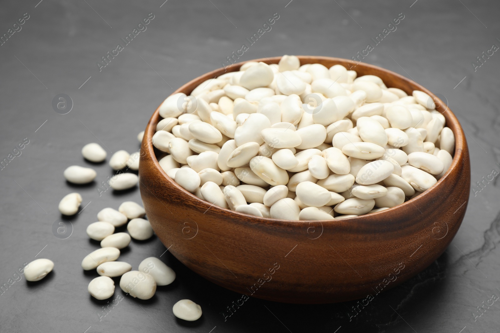 Photo of Raw white beans on black table, closeup