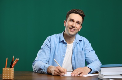 Photo of Portrait of male teacher working at table against color background