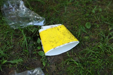 Photo of Different garbage scattered on green grass outdoors, closeup