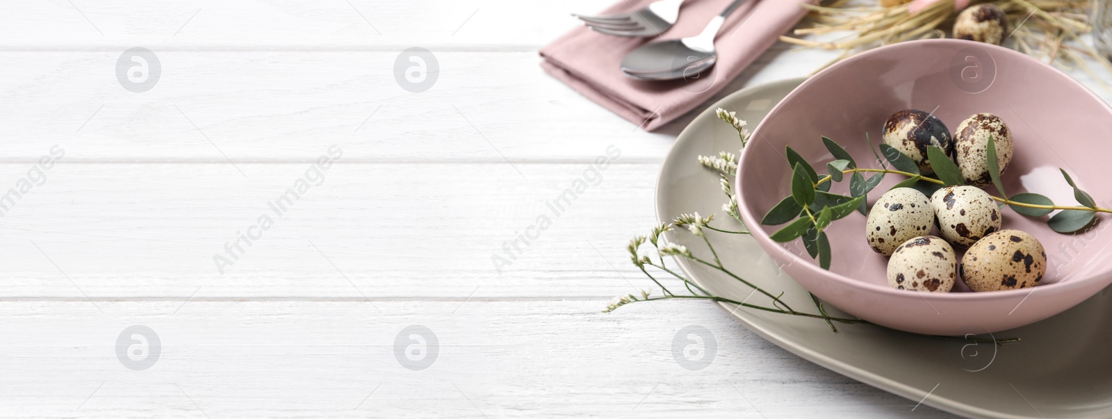 Image of Festive Easter table setting with quail eggs and floral decor on wooden background, closeup. Space for text