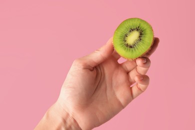 Photo of Woman holding delicious fresh kiwi on pink background, closeup