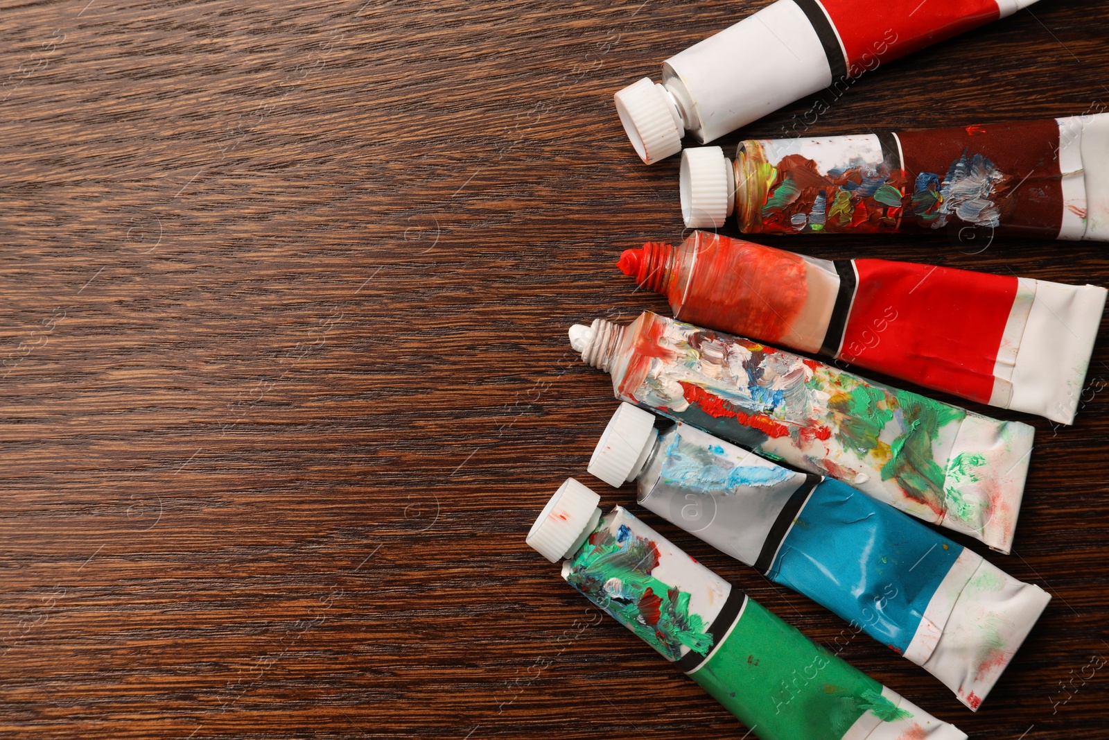 Photo of Tubes with oil paints on wooden table, flat lay. Space for text