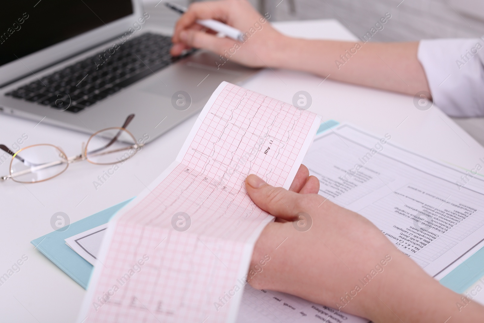 Photo of Doctor examining cardiogram at table in clinic, closeup