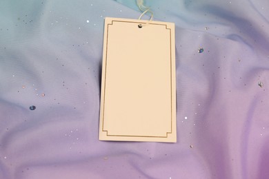 Photo of Blank white tag on color fabric. Space for text