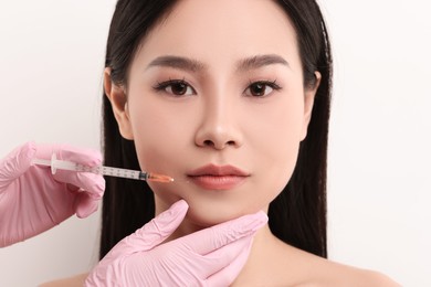 Photo of Woman getting lip injection on white background, closeup