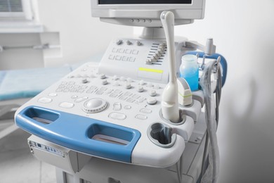 Photo of Ultrasound control panel with ultrasonic transducers and transmission gel indoors, closeup. Medical equipment