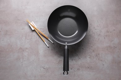 Photo of Empty iron wok and chopsticks on grey table, flat lay