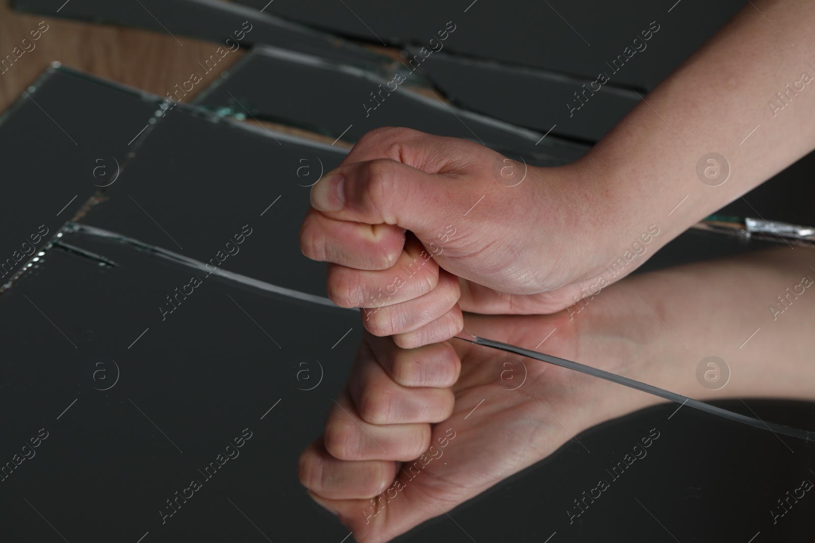 Photo of Woman hitting broken mirror with fist, closeup