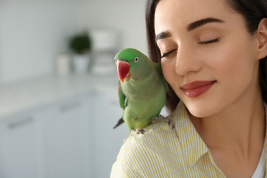 Young woman with Alexandrine parakeet indoors, closeup. Cute pet