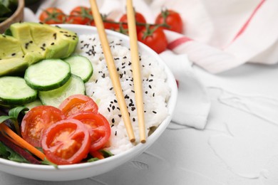 Delicious poke bowl with vegetables, avocado and mesclun on white table, closeup