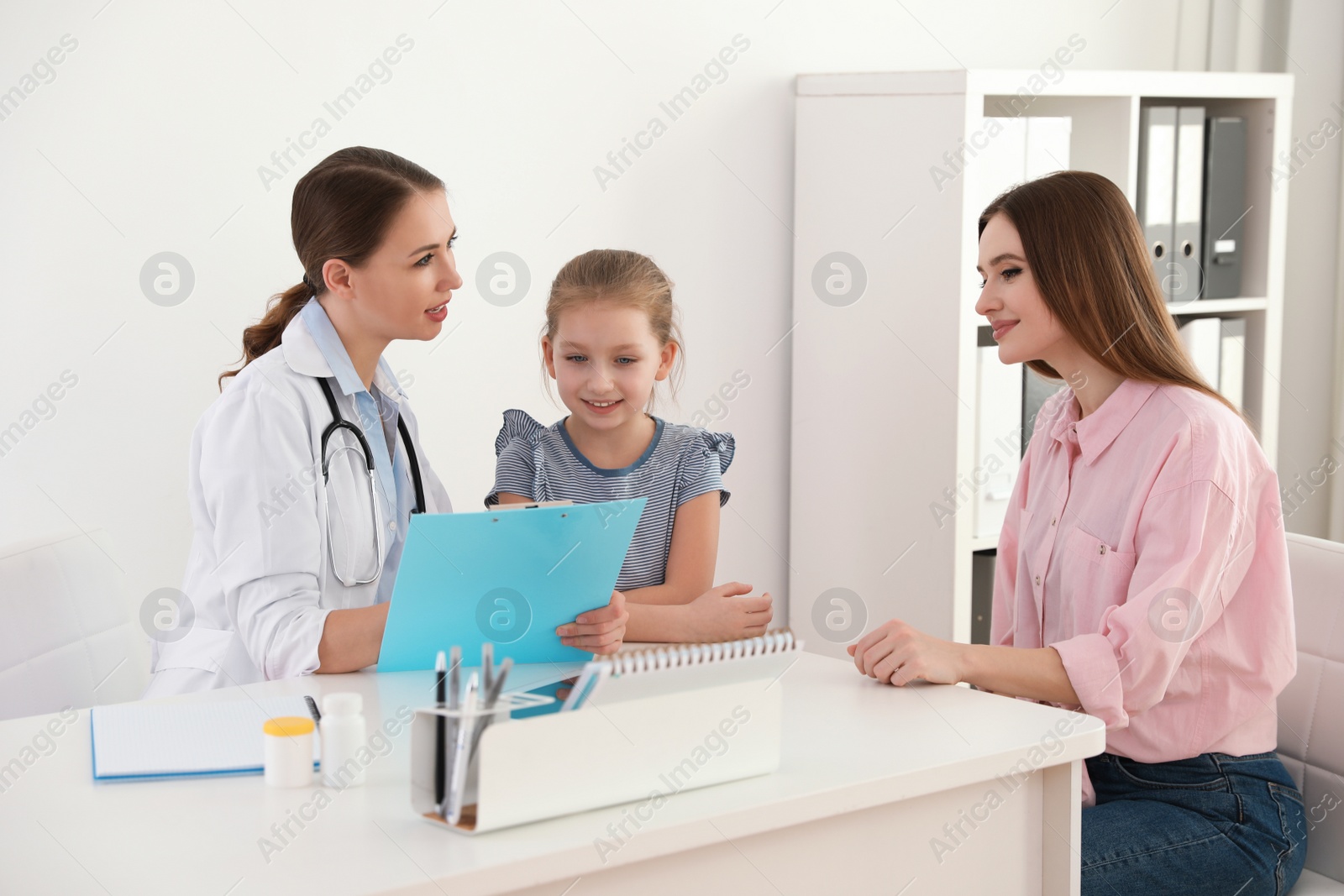 Photo of Mother and daughter visiting pediatrician. Doctor working with patient in hospital