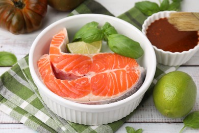 Photo of Fresh marinade, fish and lime on white wooden table, closeup