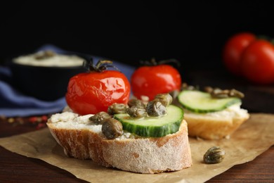 Tasty bruschettas with vegetables and capers on wooden table, closeup