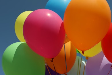 Photo of Bright colorful balloons with ribbons, closeup view