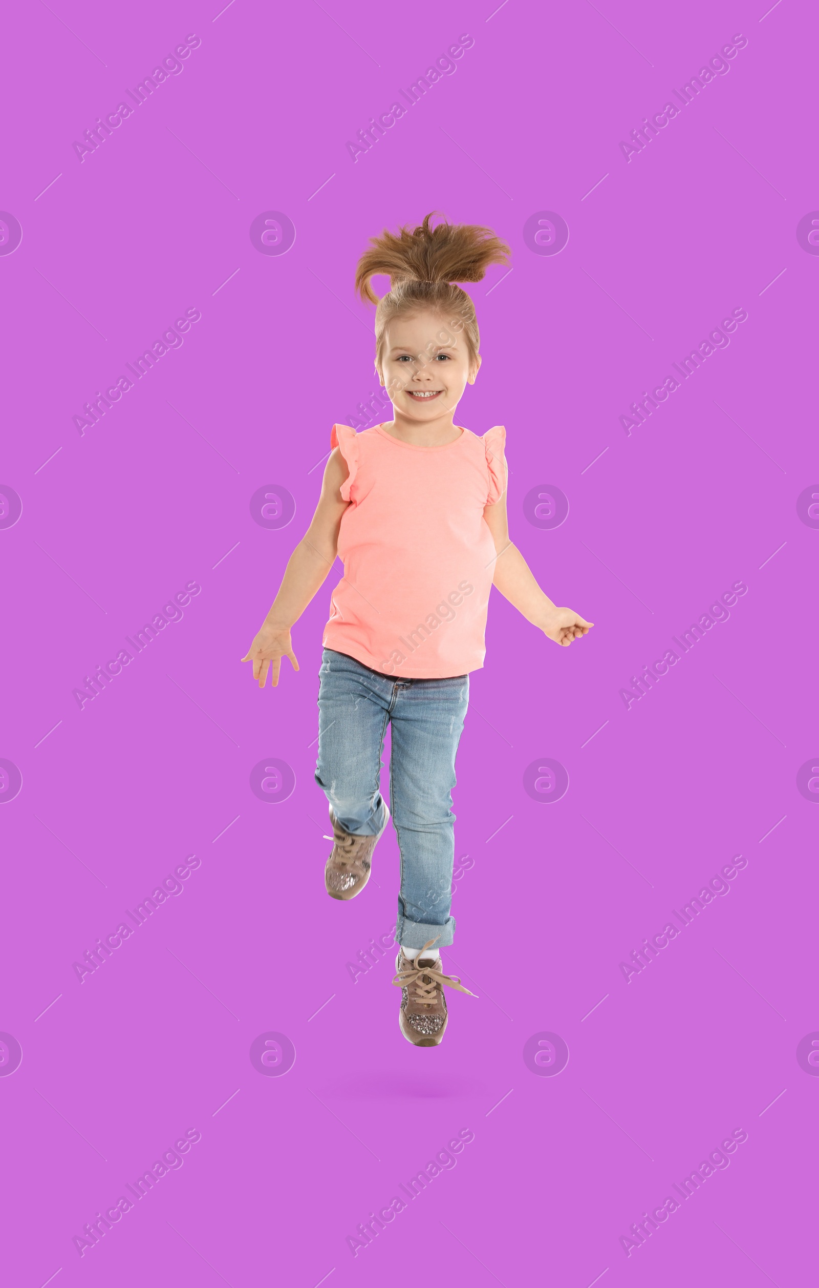 Image of Happy cute girl jumping on violet background