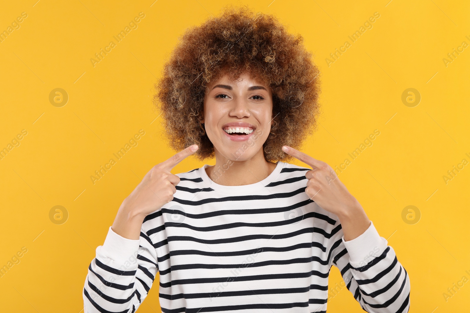 Photo of Woman showing her clean teeth on yellow background