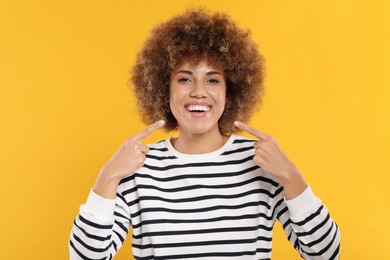 Photo of Woman showing her clean teeth on yellow background