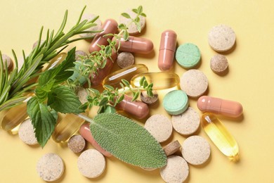 Photo of Different pills and herbs on light yellow background, flat lay. Dietary supplements