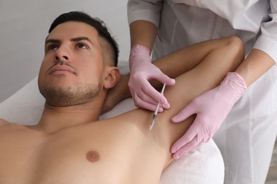 Photo of Cosmetologist injecting man's armpit in clinic. Treatment of hyperhidrosis