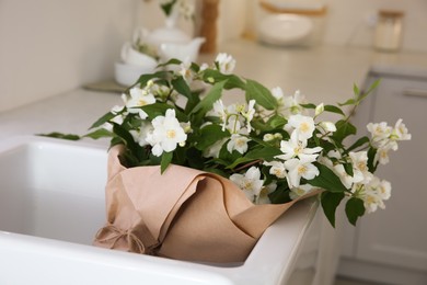 Photo of Bouquet with beautiful jasmine flowers in kitchen sink