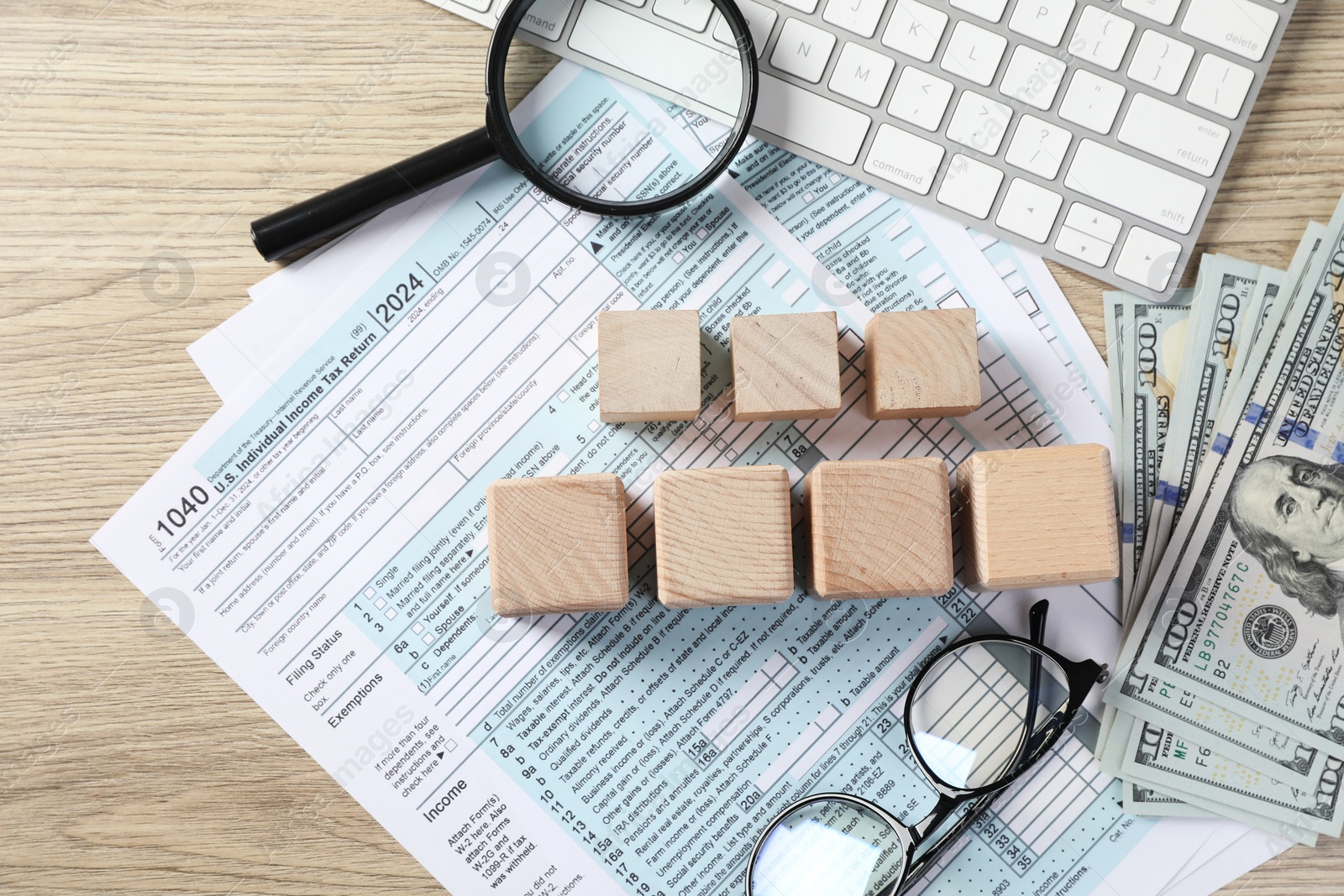 Photo of Taxes. Cubes, money, glasses and documents on light wooden table, flat lay