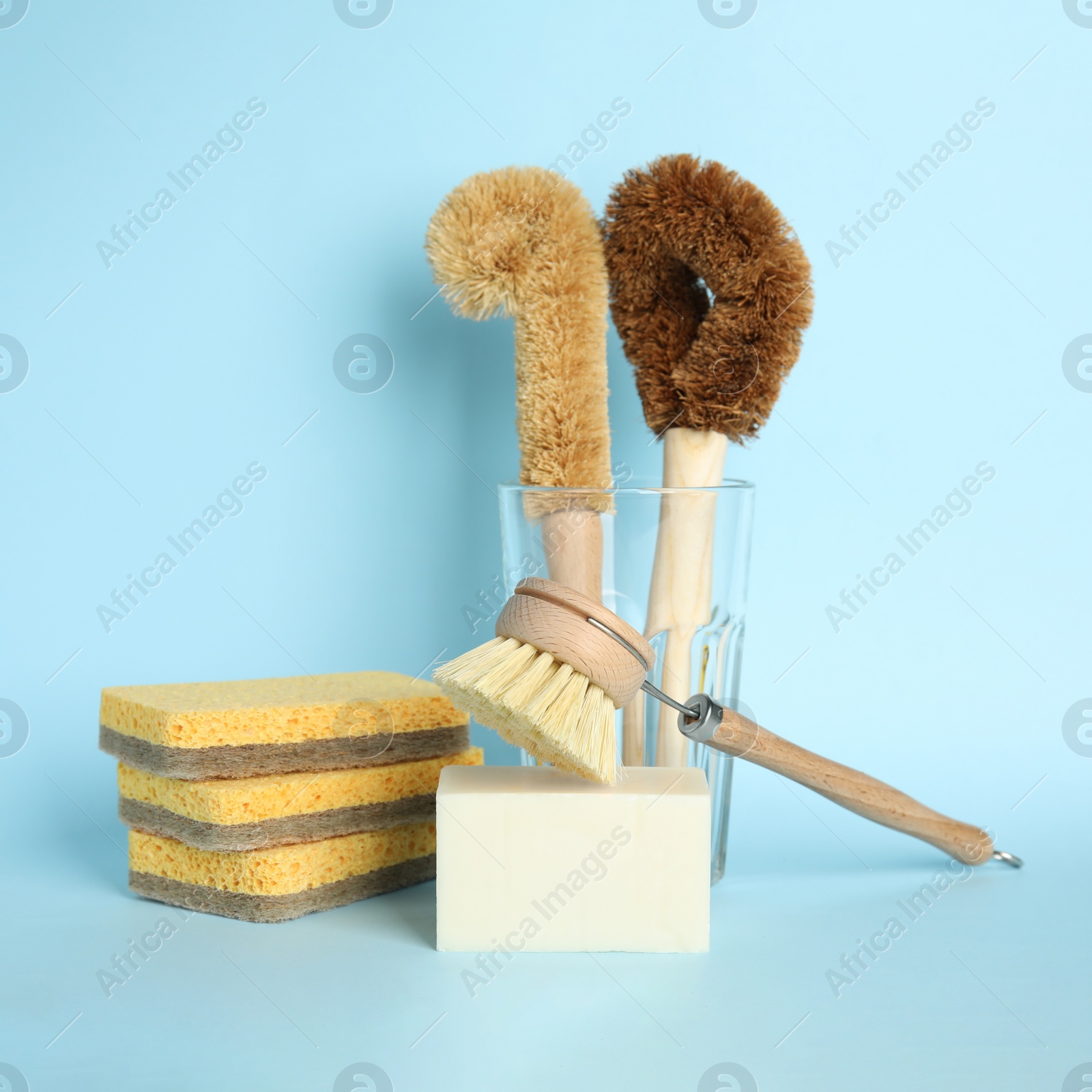 Photo of Cleaning supplies for dish washing on light blue background