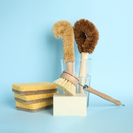Photo of Cleaning supplies for dish washing on light blue background