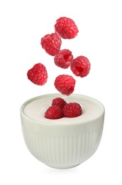 Delicious ripe raspberries falling into bowl with yogurt on white background