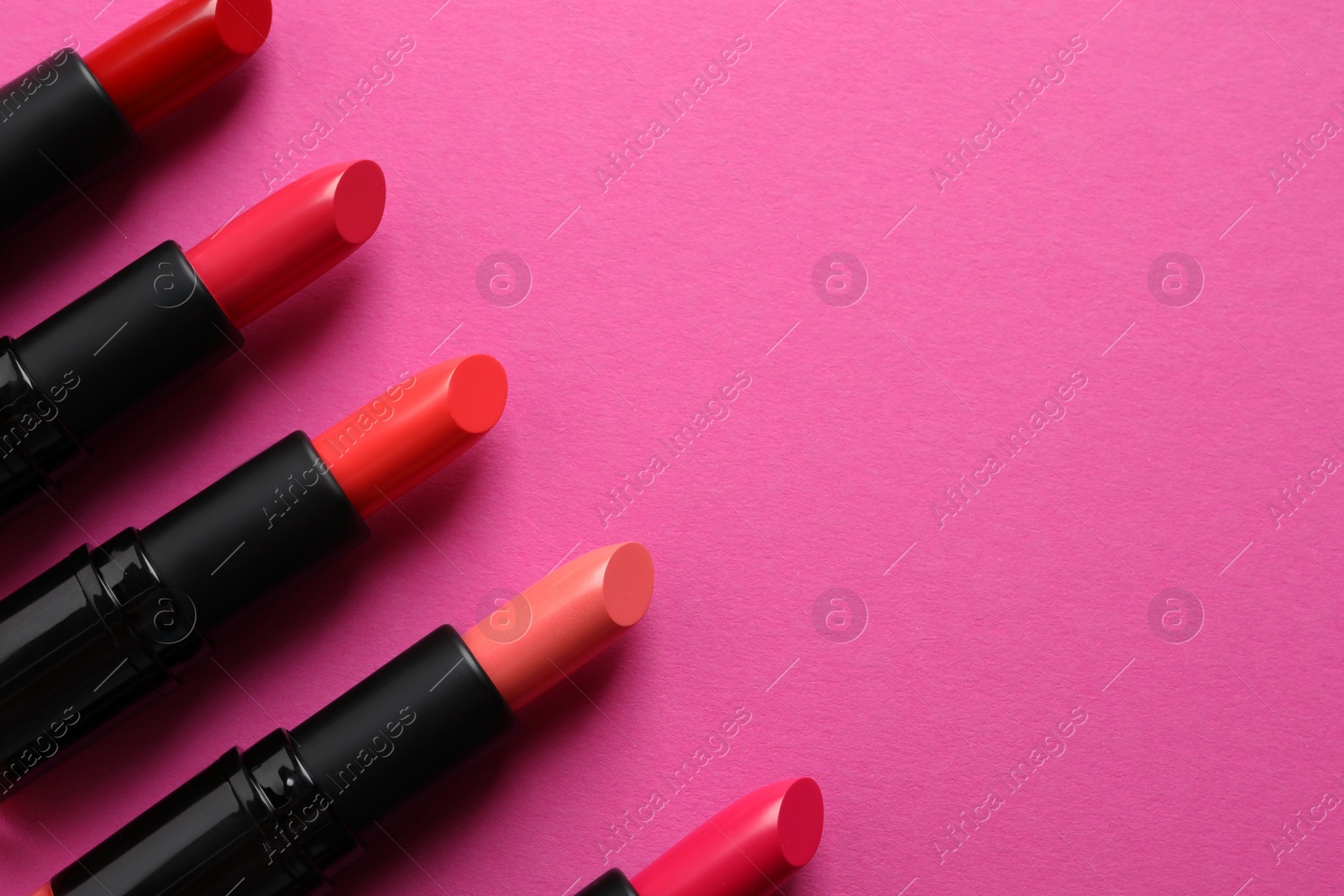 Photo of Beautiful lipsticks on pink background, flat lay. Space for text