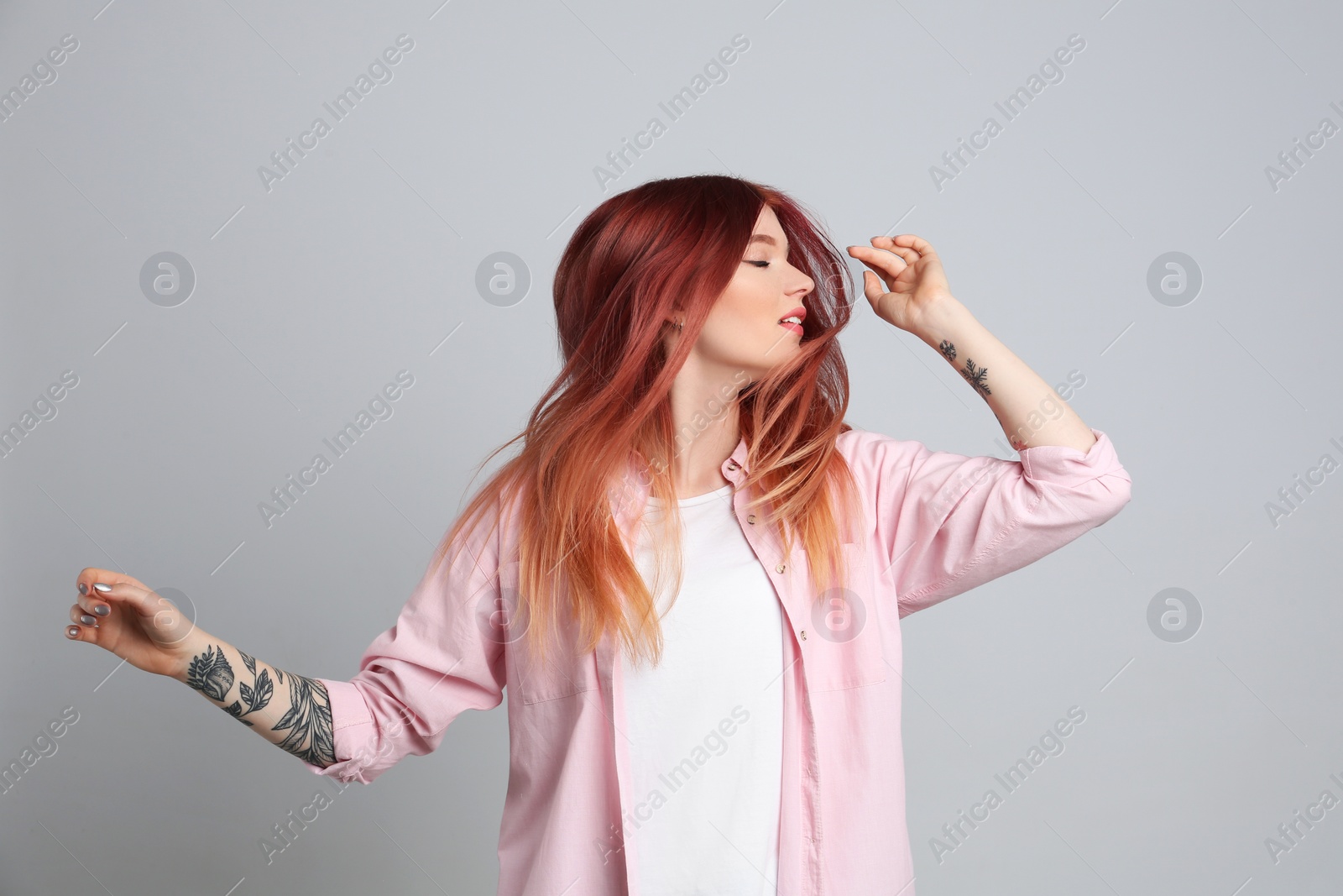 Photo of Young woman with bright dyed hair on grey background