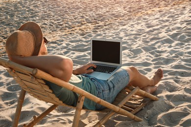 Photo of Man with laptop relaxing in deck chair on beach