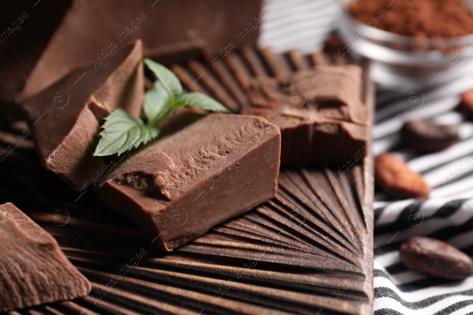 Photo of Pieces of tasty milk chocolate and mint on table, closeup