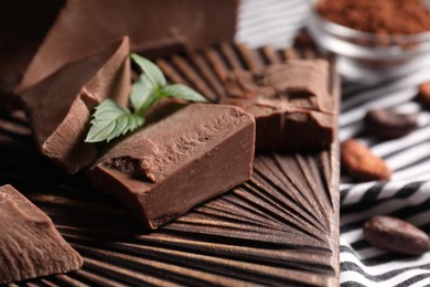 Photo of Pieces of tasty milk chocolate and mint on table, closeup
